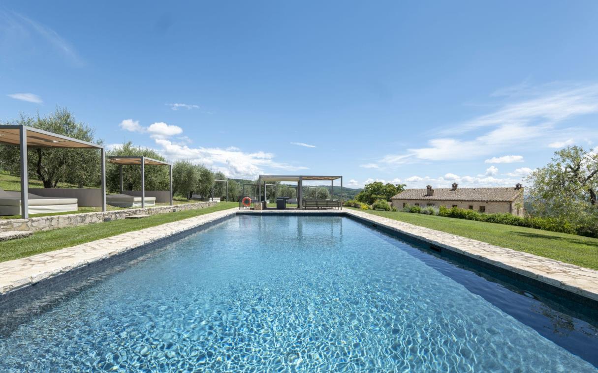 Outdoor pool surrounded by day beds with lounge area at one end