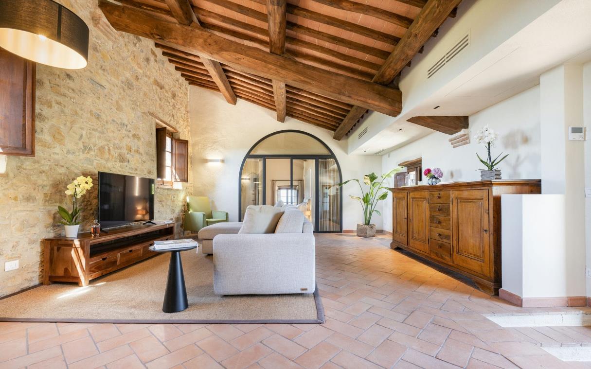 TV room with lounges, arched doorways and slanted, wood-beamed ceiling