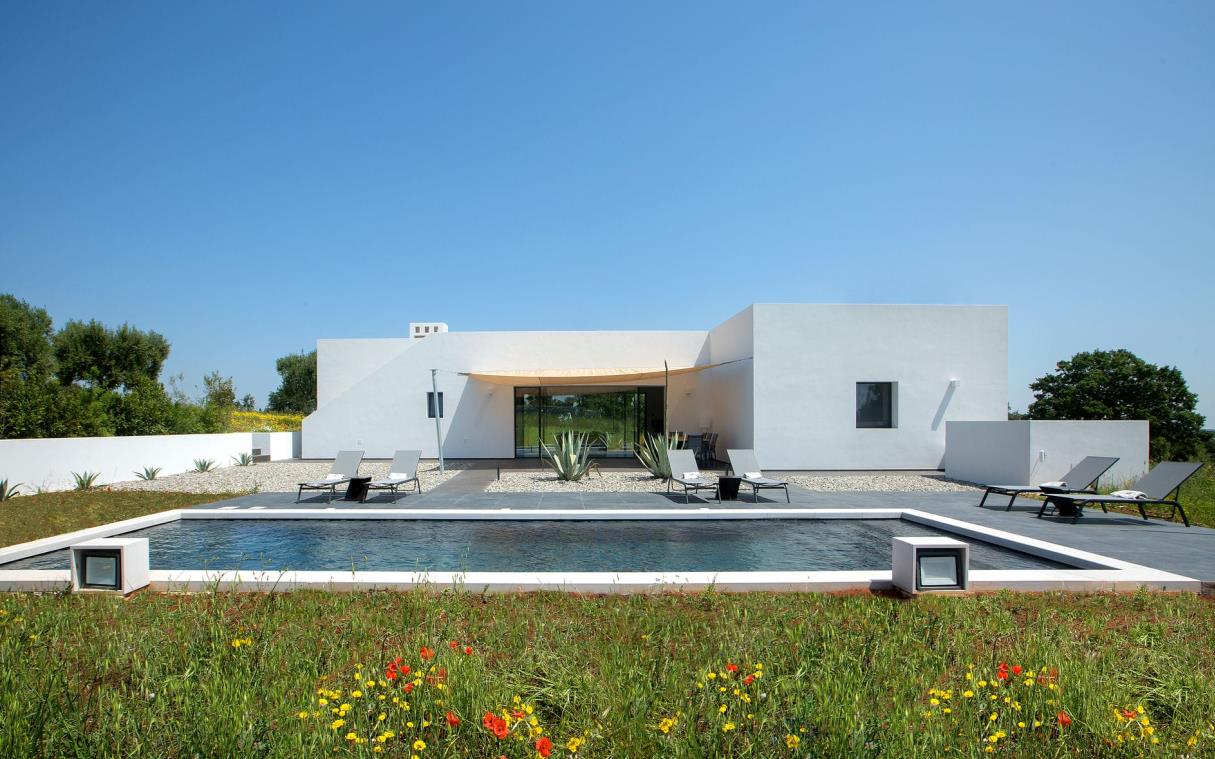 Single-storey villa with rectangular swimming pool and outdoor living area.