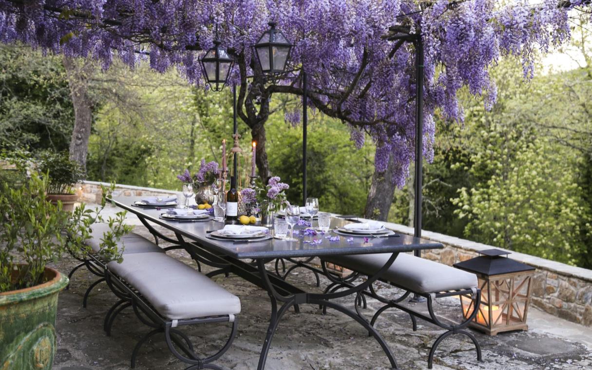 Outdoor dining table beneath wisteria